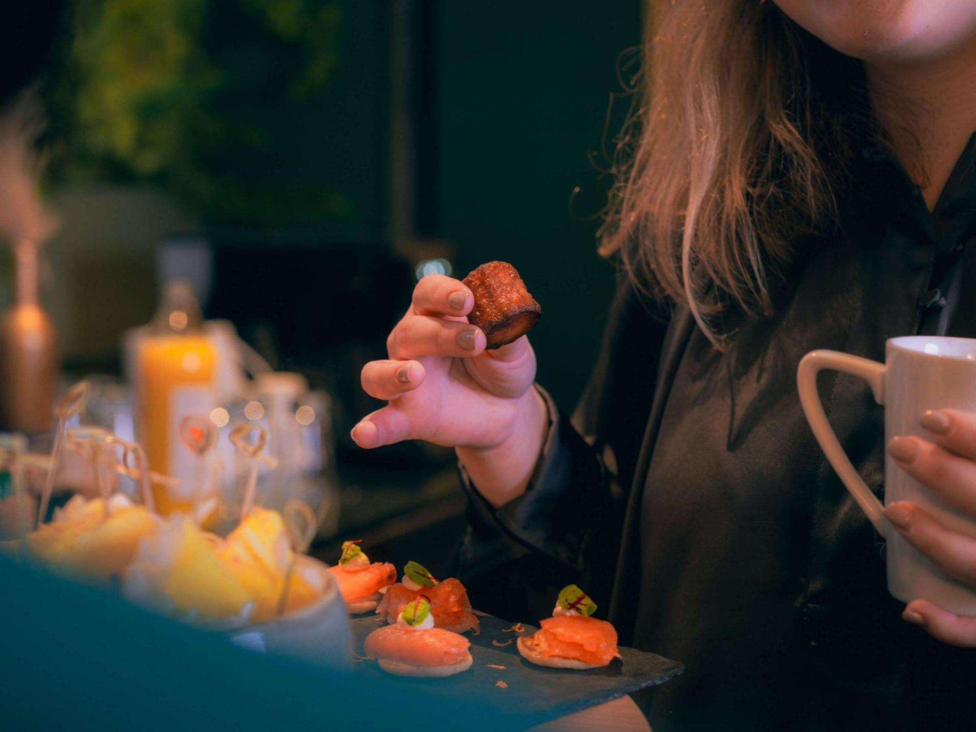 Nest Paris La Defense - Mgallery Puteaux Exteriör bild A woman holding a piece of sushi